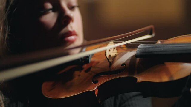 closeup portrait of female violinist in old opera house, woman is playing violin