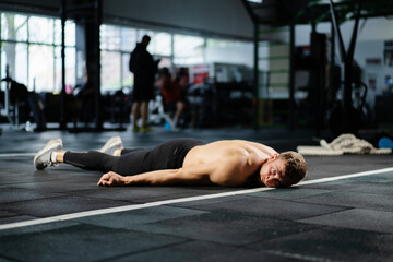 a man resting lies on the floor in the gym, he is very tired and feels bad after a workout, cross...