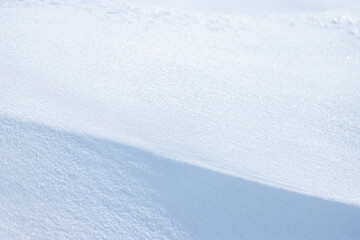 Beautiful winter background with snowy ground. Natural snow texture. Wind sculpted patterns on snow surface. Closeup top view with copy space.