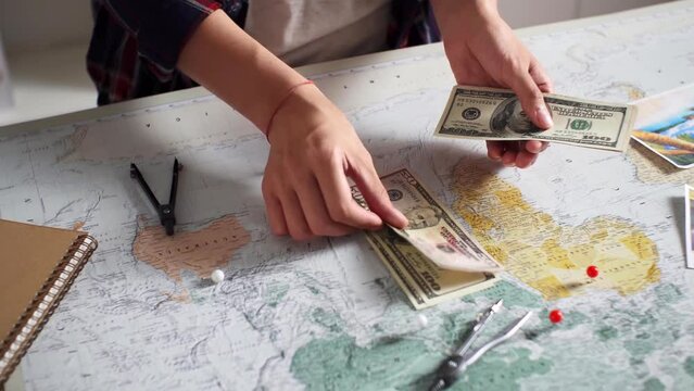 Traveler tourist counts cash and dollars A tourist girl going on a trip for a long time counts money dollars accumulated over a long time. Cash counting on world map background

