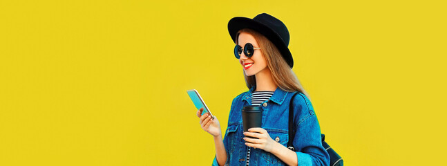Portrait of stylish happy smiling young woman model with smartphone wearing black round hat, jean...