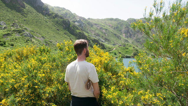 Hombre joven haciendo pip&iacute; en paisaje monta&ntilde;oso con lago