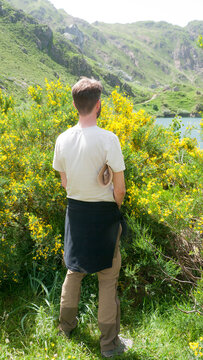 Hombre joven haciendo pip&iacute; en paisaje monta&ntilde;oso con lago