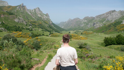 Hombre blanco de ruta en caballo por valle verde entre montañas rocosas