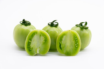 Whole and halved fresh green unripe tomatoes isolated on white background.