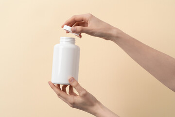 Femal hand holds a bottle of medication pills