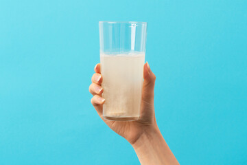 A glass with effervescent tablet on the blue and green background