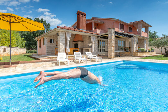 Croatia, Istria, Pula, senior man jumping into the pool in front of holiday house