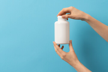 Female hand holding bottle of medication pills