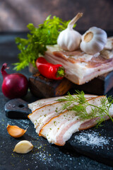 Chopped salted bacon or sliced pork belly with herbs, peppers, onions and garlic. Black stone countertop.
