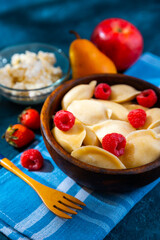 Dumplings, filled with strawberries and raspberry in wooden bowl. Varenyky, vareniki, pierogi, pyrohy - dumplings with filling. 