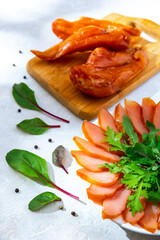 Dry-cured chicken meat or carpaccio on a plate and cutting board with basil and arugula on a white background.