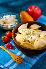 Dumplings, filled with strawberries and raspberry in wooden bowl. Varenyky, vareniki, pierogi, pyrohy - dumplings with filling. 