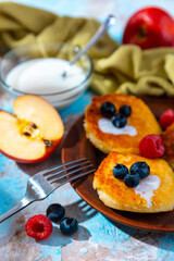 Homemade сottage cheese pancakes, syrniki with blueberry and raspberry on blue background.