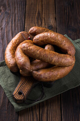 Fototapeta premium Closeup of homemade sausages on wooden cutting board. Rustic old wooden table top.