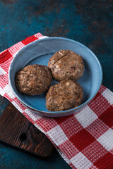 Raw meat cutlets in a plate on a wooden cutting board. Rustic old wooden table top.