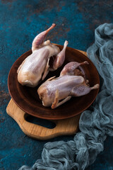 Two raw quails preparation on wooden cutting board.