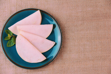 round thinly sliced pieces of meat sausage ham on a blue plate