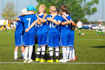 Sporty players huddling in a circle on the field. Motivated youth soccer team cheering on court....