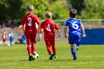Football soccer children tournament match. Kids practicing football on grass field. Group of school children running and kicking soccer ball on summer soccer league game