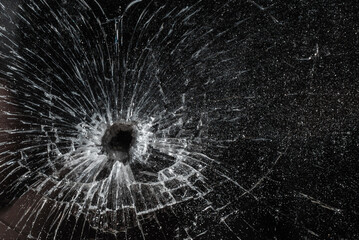 Bullet hole in a glass on the black background.closeup.