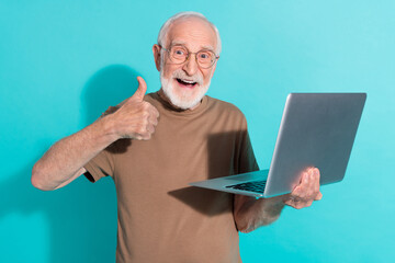 Portrait of attractive trendy cheerful grey-haired man using laptop showing thumbup isolated over...