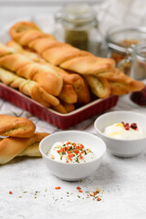 Fried bread sticks with sour cream sauce and spices on a light table. Serving homemade pastries with stuffing