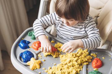 Cute little boy playing with kinetic sand. Development of fine motor skills. Early sensory education. Activities Montessori. Sensory plays at home.