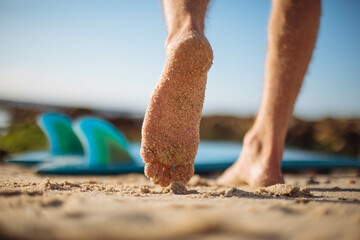 feet on the beach with surfboard