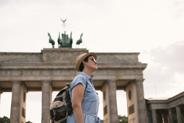 A tourist with a backpack visiting the Brandenburg Gate in Berlin in Germany - obrazy, fototapety, plakaty