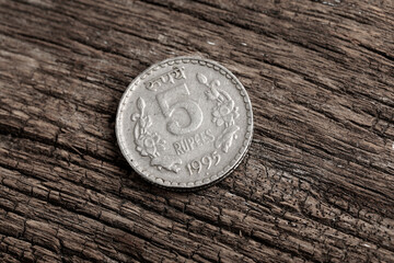 Indian old five rupees coin on wooden background.