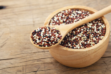 Quinoa in spoon and bowl on wooden table