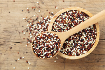 Quinoa in spoon on bowl on wooden background