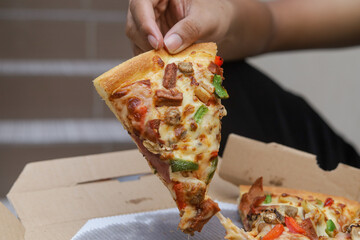 hand taking a slice of pizza, selective focus