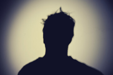 Shadow of a man from the night light of a flashlight on a white wall. Silhouette of a man head from the light of a lamp