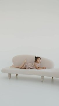 Asian baby girl sitting on the sofa and laughing, vertical video