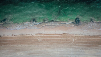 Aerial vertical view to the seashore in the morning. Empty sand beach and beautiful waves. 