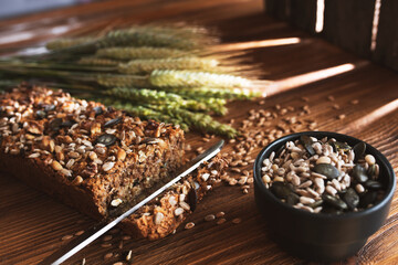 Homemade grain bread and ears of corn on wood with light reflections. Short depth of field. 