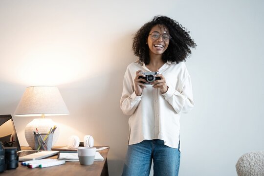 Young mixed race woman photographer with a professional camera in office
