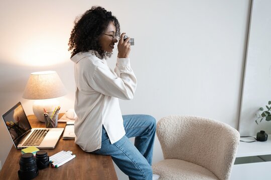 Young mixed race woman photographer with a professional camera in office