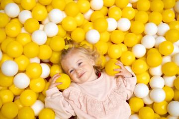 Funny cute little caucaisian blonde baby girl,toddler, smiling kid having fun in ball pool,playing...