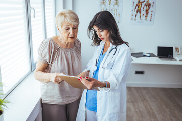 Senior woman patient talking with female doctor during a medical consultation at the hospital...