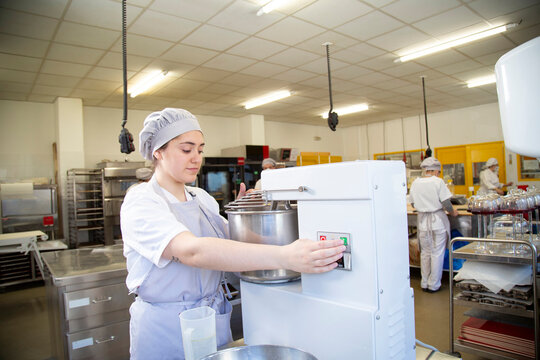 Woman turning on mixer in bakery