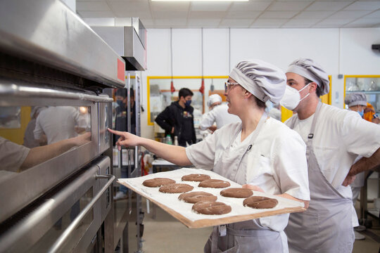 Woman with raw bread turning on oven