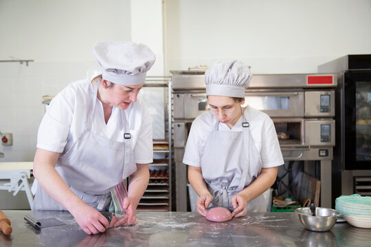 Women greasing dough in bakery