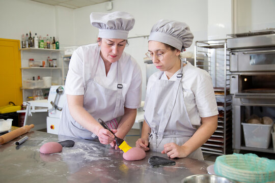 Women greasing dough in bakery
