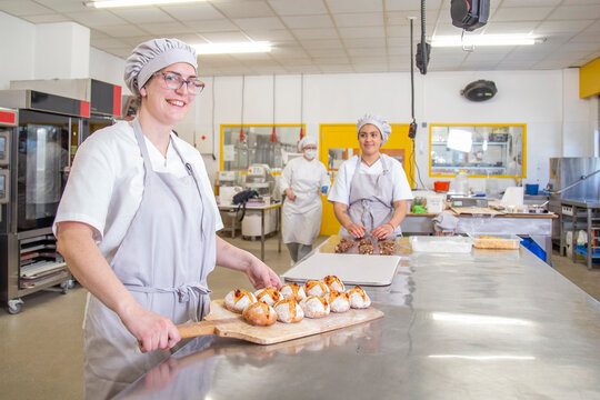 Positive woman with baked bread in bakery school