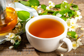 Herbal jasmin flower tea. Jasmine green tea in glass teapot and white tea cup, with fresh jasmin blossom