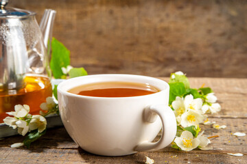 Herbal jasmin flower tea. Jasmine green tea in glass teapot and white tea cup, with fresh jasmin blossom