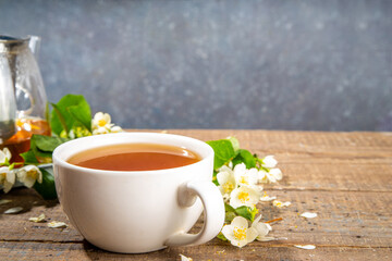 Herbal jasmin flower tea. Jasmine green tea in glass teapot and white tea cup, with fresh jasmin blossom